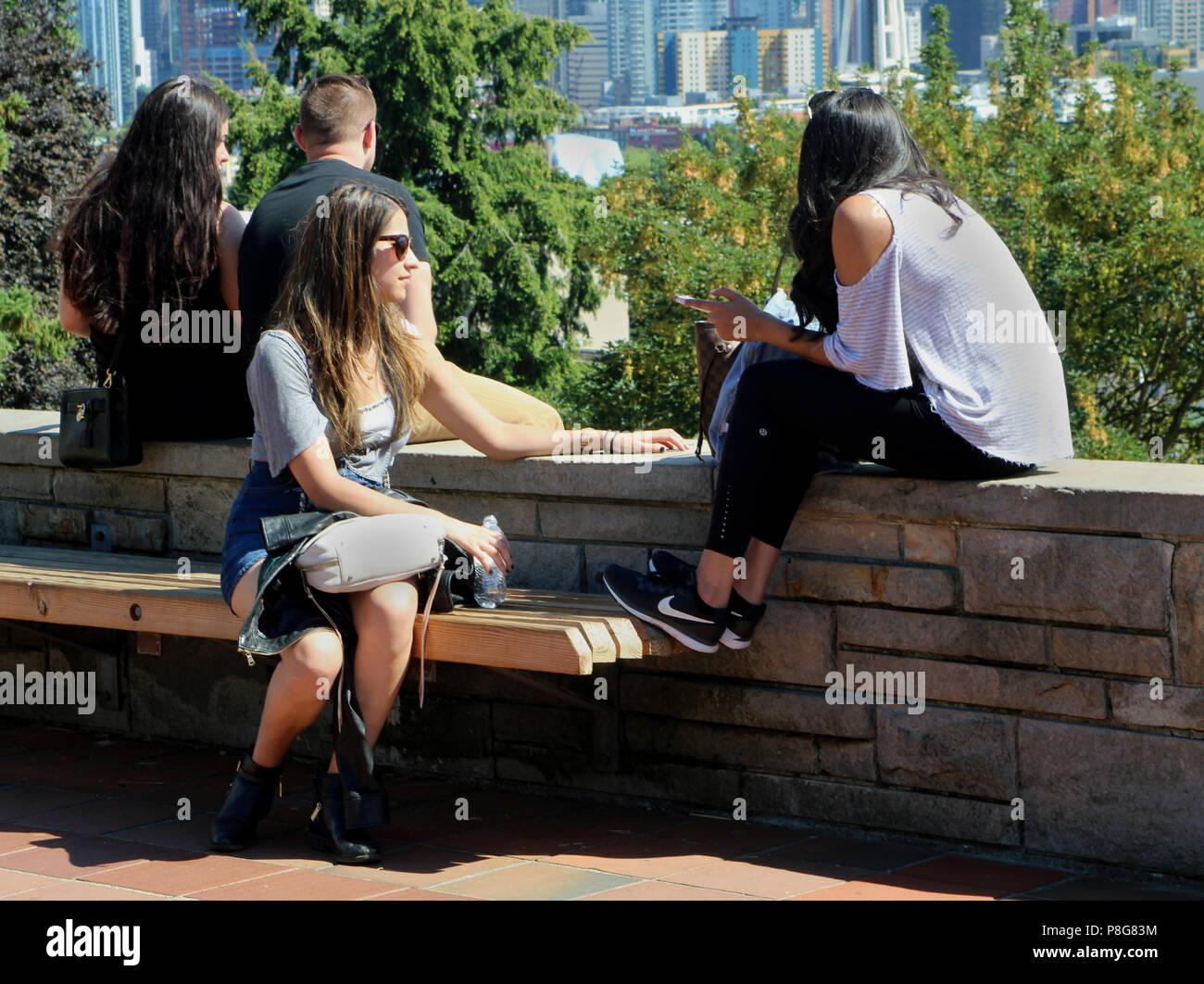 Junge Frauen Plaudern und Entspannen an einem Park, genießen den Blick auf die Skyline von Seattle und das gute Wetter. Stockfoto