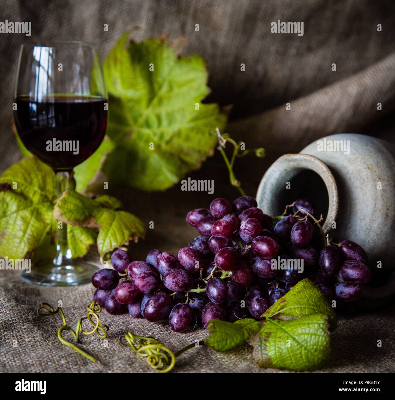 Stillleben von Trauben in einer Urne mit einem Glas Rotwein Stockfoto