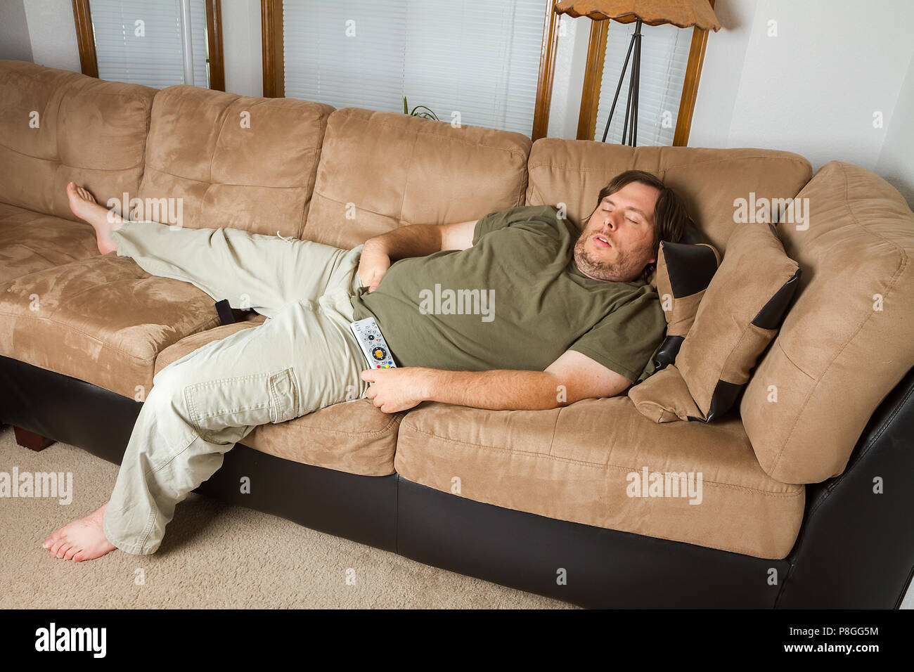 Fat man schlafen auf der Couch mit seiner Hand seine Hose nach unten  Stockfotografie - Alamy