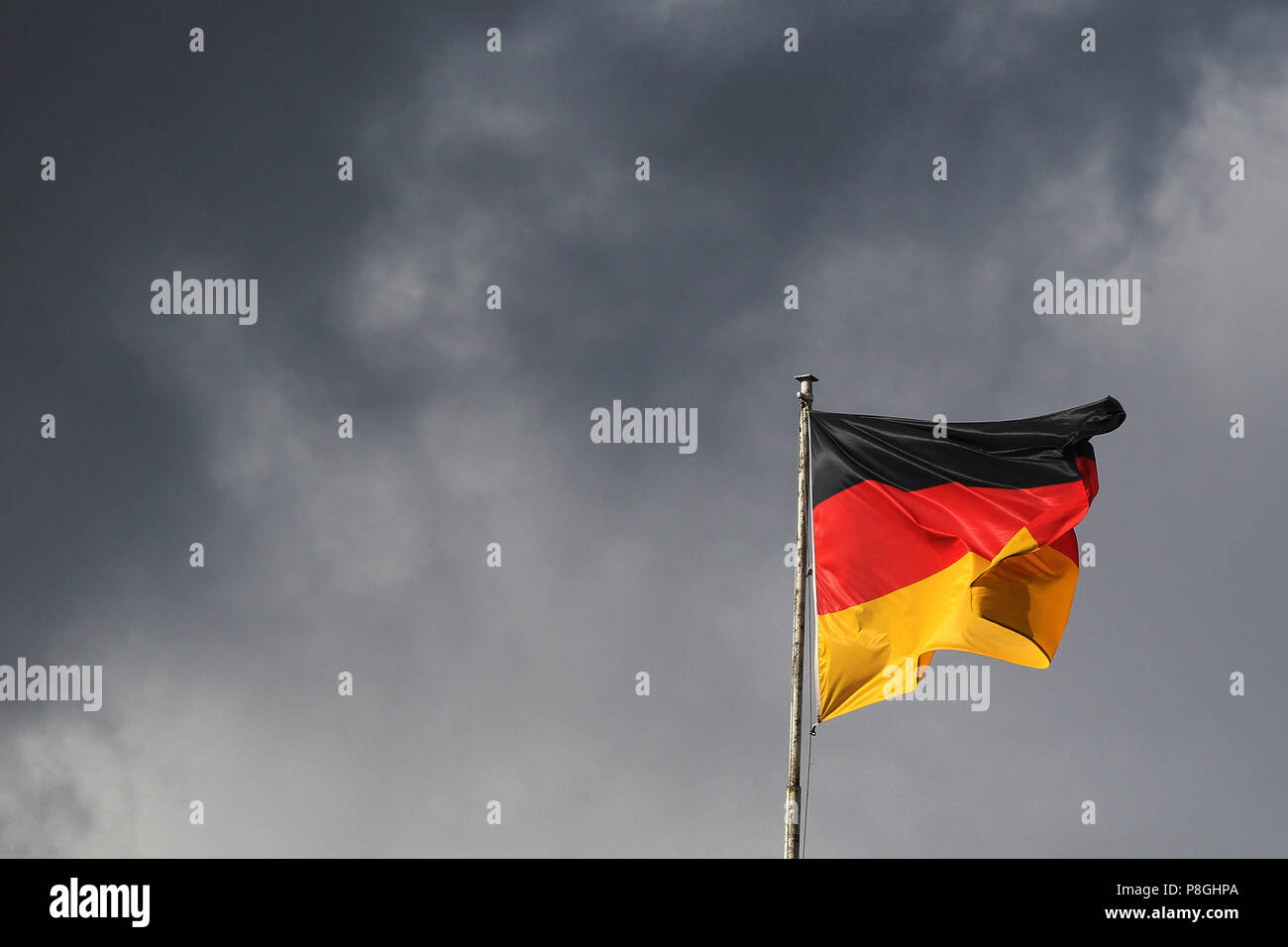 Hoppegarten, Deutschland, Deutsche Flagge weht vor dunklen Himmel Stockfoto