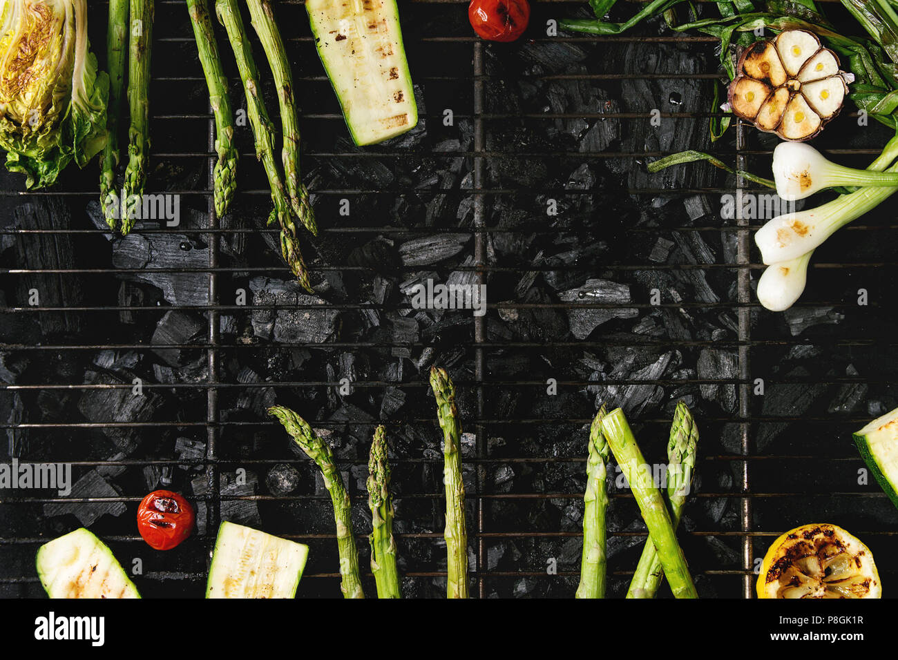 Gegrilltes Gemüse grüner Spargel, Knoblauch, Zitrone, Frühlingszwiebeln, Zucchini, Tomaten, Salat auf BBQ Grill Rack über Kohle. Ansicht von oben, Platz. Ba Stockfoto