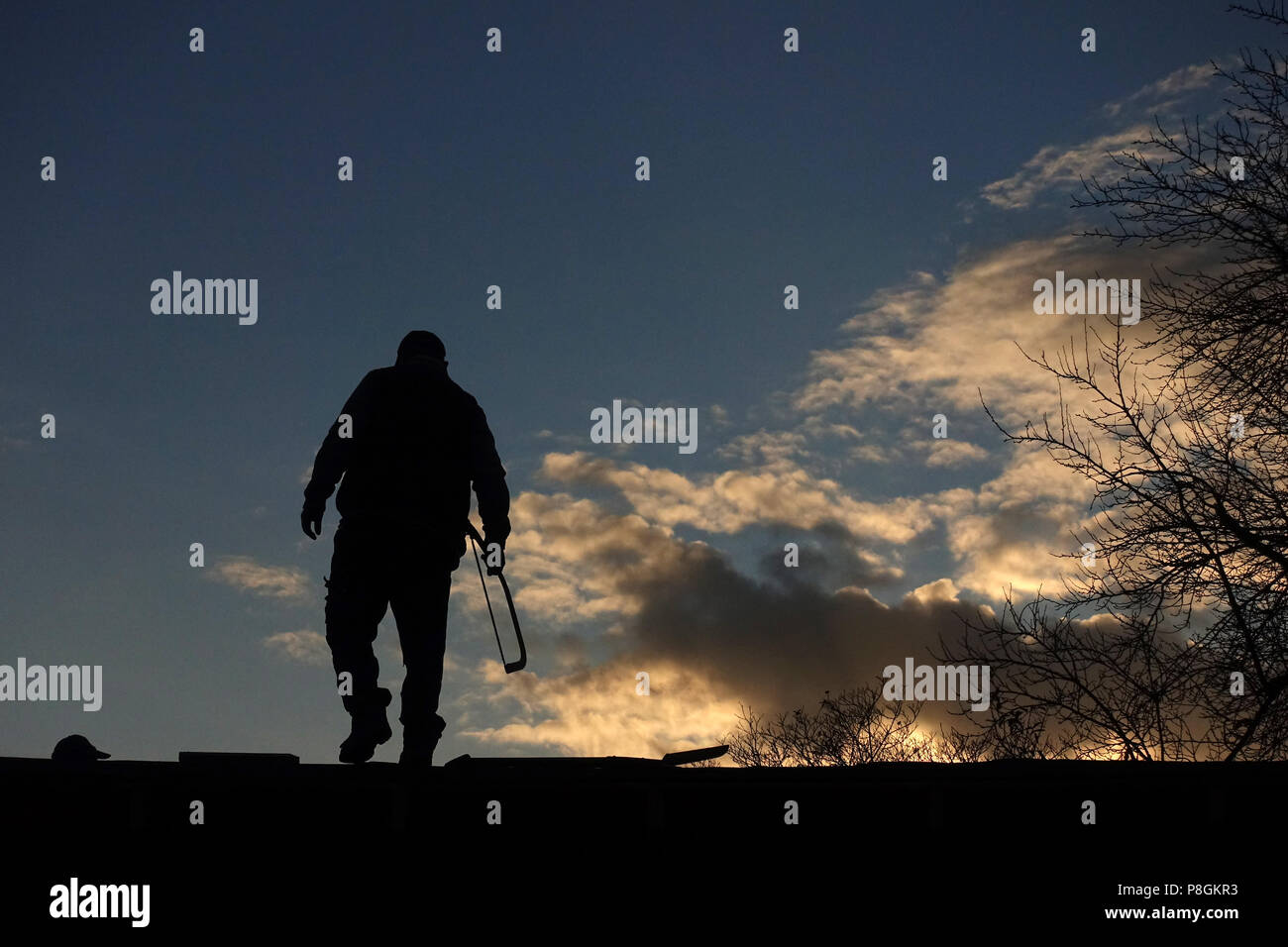 Berlin, Deutschland, Silhouette, Handwerker steht mit einer Säge auf dem Dach eines Pavillon Stockfoto