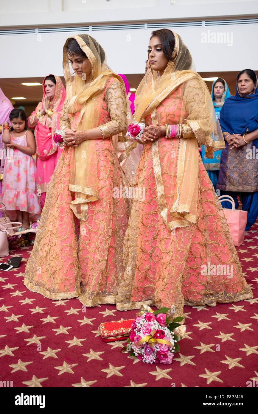 Zwei Frauen in identischen Kleider an einem Hochzeit Zeremonie im Tempel in der Sikh Gesellschaft in Richmond Hill, Queens, New York City. Stockfoto