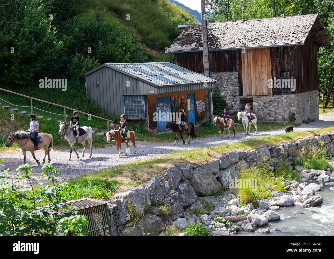 Pferde und Ponys einer Reitschule, die am Fluss Dranse in Morzine Haute-Savoie Portes du Soleil Frankreich geritten wird Stockfoto