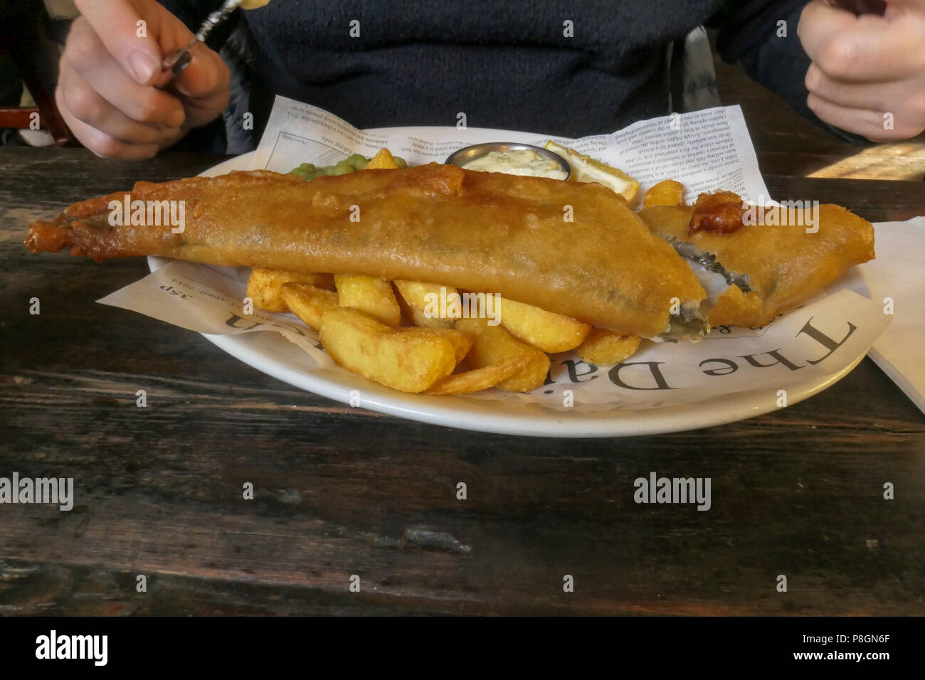 Platte von Panierten Fisch und Chips mit Erbsenpüree und Sauce Tartar serviert in einem Restaurant Stockfoto