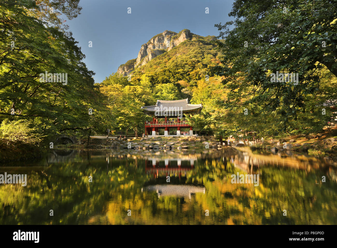 Buddhistische Tempel neben einem ruhigen Fluss mit einem Berg im Hintergrund. Stockfoto