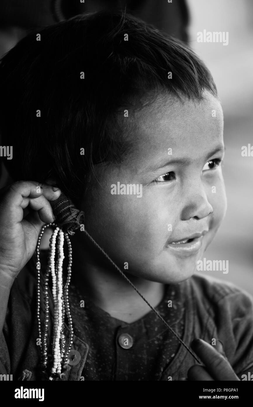 Ein Kind aus dem Stamm ANN spielt mit Wulst Arbeit in einem Dorf in der Nähe von KENGTUNG oder KYAINGTONG - MYANMAR Stockfoto