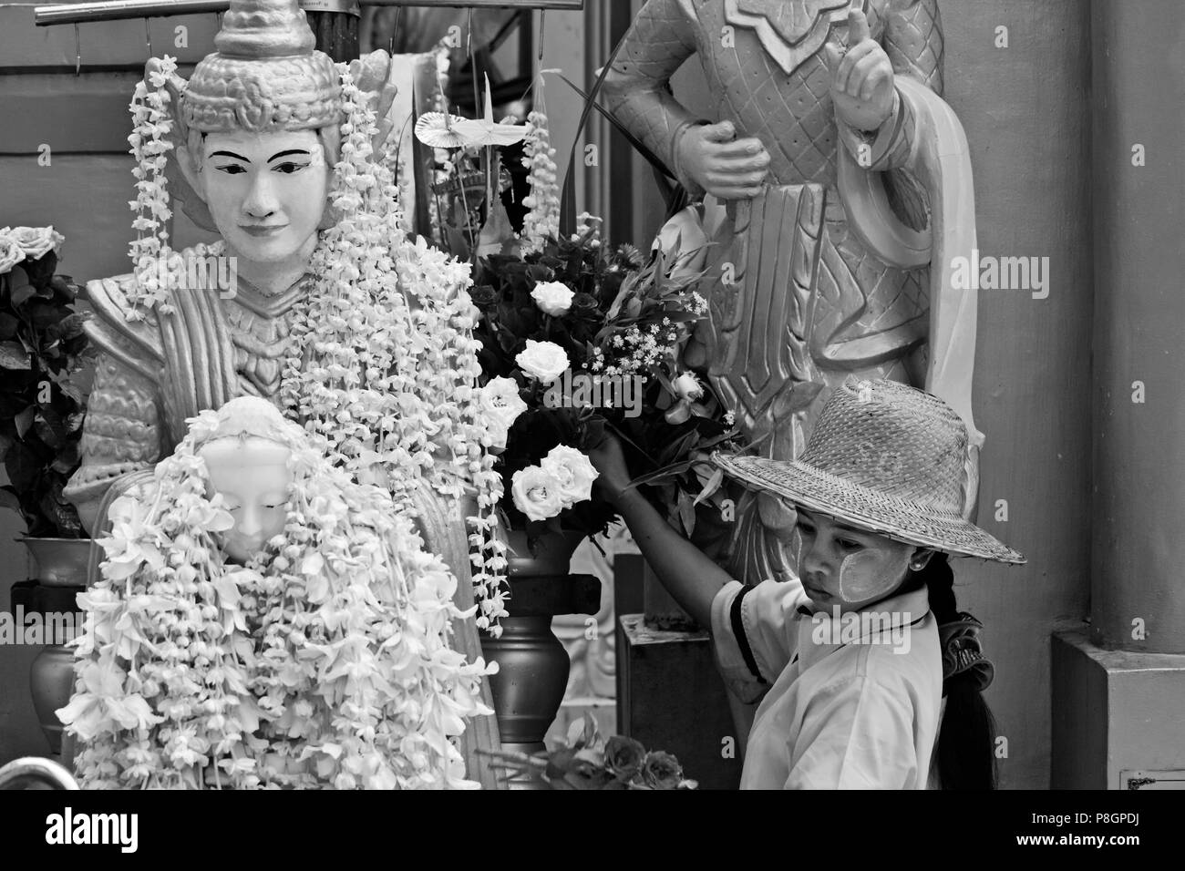 Eine BUDDHA-STATUE bedeckt mit Blumen an der SHWEDAGON PAYA oder Pagode aus dem Jahre 1485 - YANGON, BIRMA Stockfoto