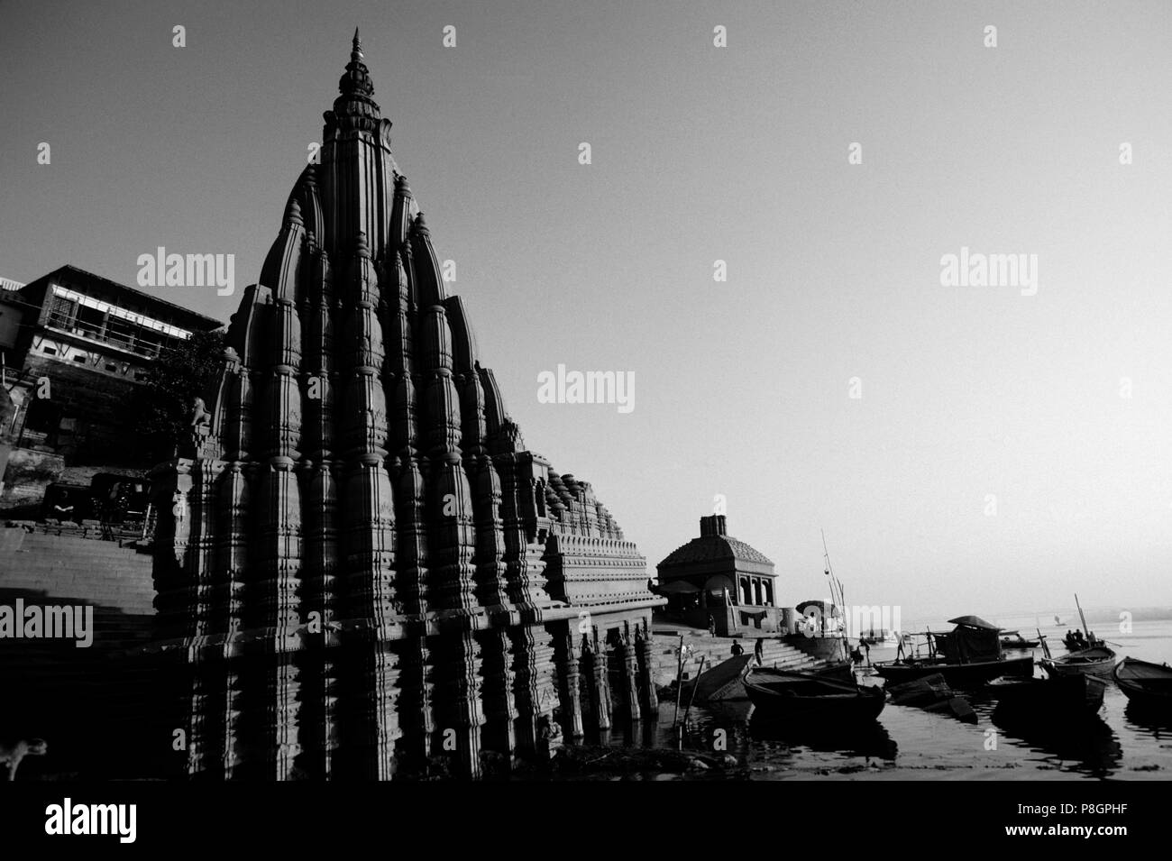 Ein Hindu Tempel erhebt sich über Kanus auf dem GANGES - VARANASI (Benares), Indien Stockfoto