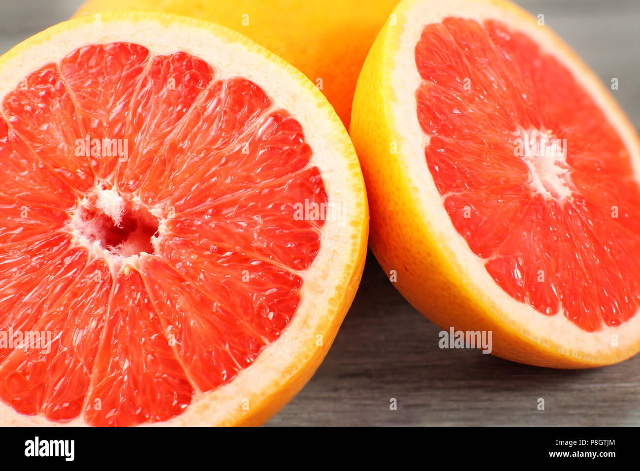 Nahaufnahme von rosa Grapefruits halbieren, auf grau Holzschreibtisch. Stockfoto