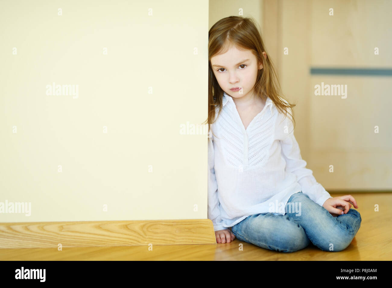 Trauriges kleines Mädchen auf einer Etage zu Hause sitzen Stockfoto