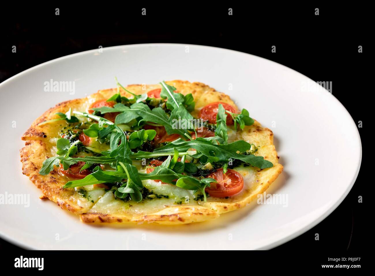 Dünne Kartoffel- und Mehlpfannkuchen mit Rucola- und Kirschtomate Stockfoto