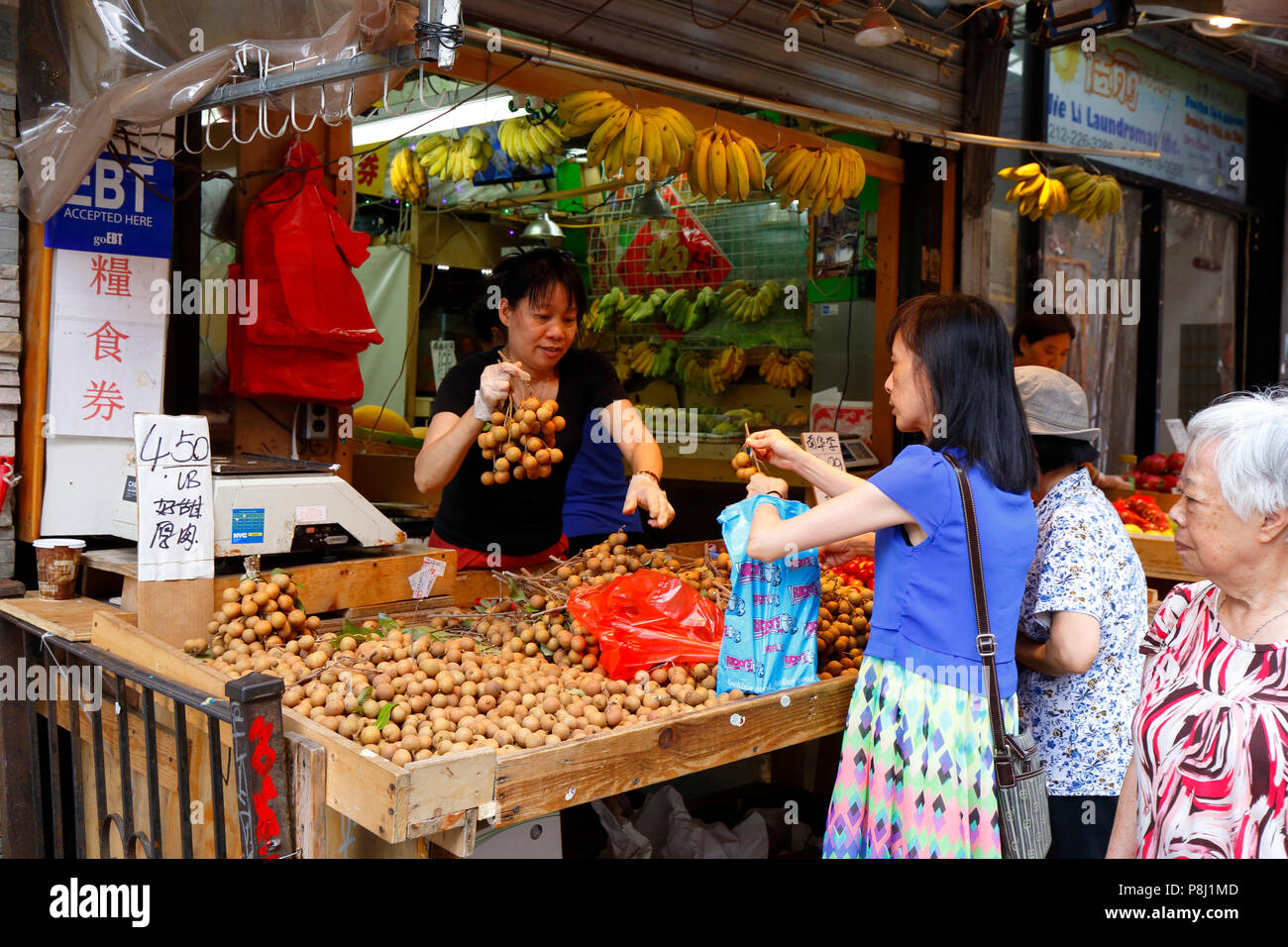 Leute kaufen Longanfrüchte in einem New York City Manhattan Chinatown Obst und Produkte Verkäufer. 華埠, 紐約, 唐人街 Stockfoto
