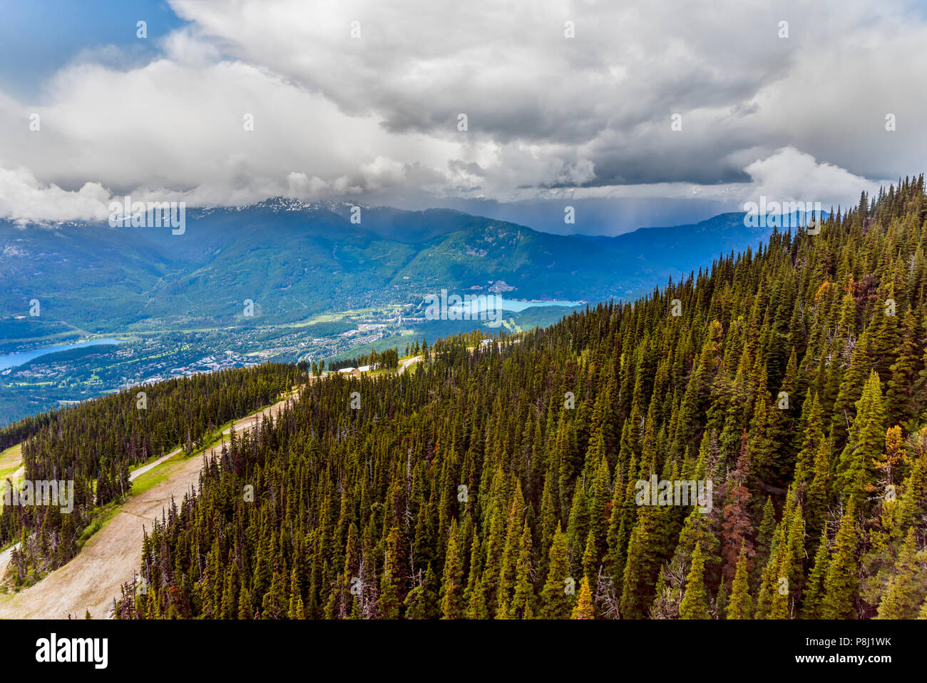 Ein Blick von Oben auf die Landstraße und das Dorf in den Bergen zwischen zwei Seen, von einem dichten Nadelwald, Schnee auf der Oberseite des Mou umgeben Stockfoto