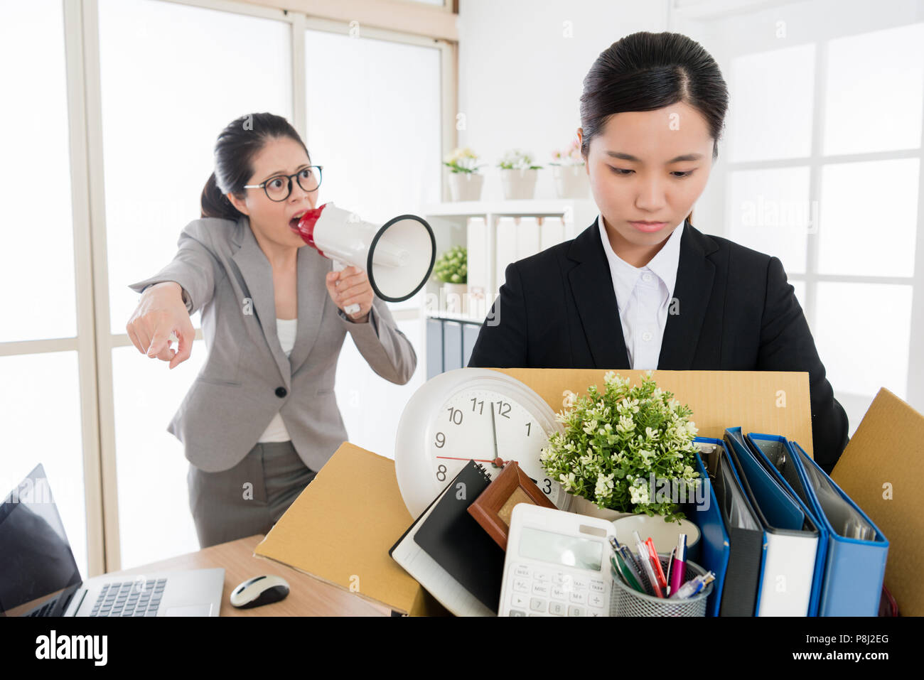 Asiatische Frau Mitarbeiter durch die strengen Boss ausgeschimpft und Ihr Unternehmen Material mit einem, das Büro zu verlassen. Stockfoto