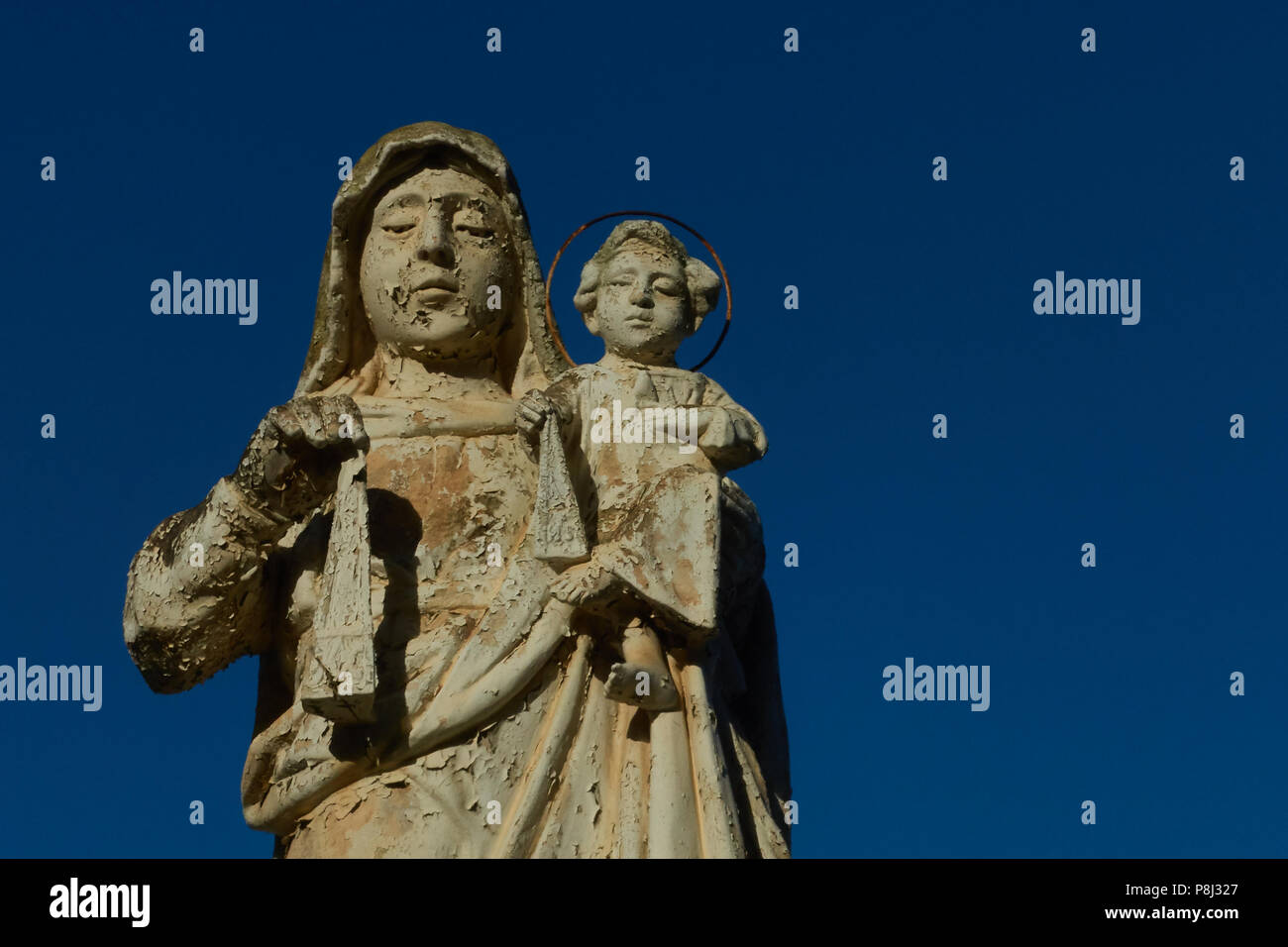 Ein Wetter abgenutzt Statue nach unten in die addolorata Cemetery, Paola, Malta, mit einem klaren blauen Himmel hinter Stockfoto