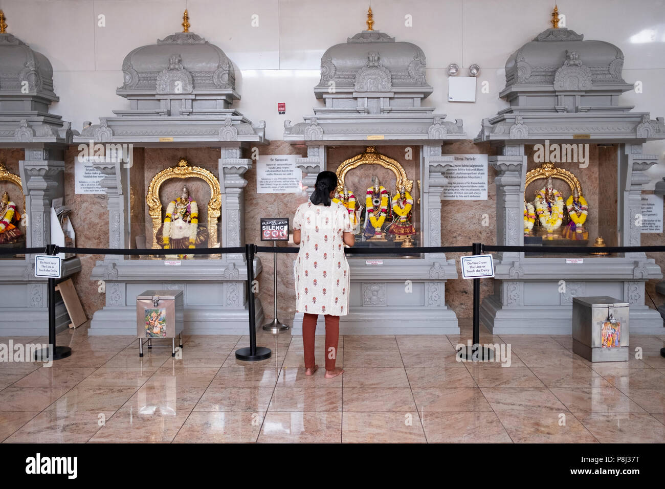 Eine Frau betend und meditierend vor Statuen der Götter und Göttinnen im hinduistischen Tempel Gesellschaft in Flushing, Queens, New York City. Stockfoto