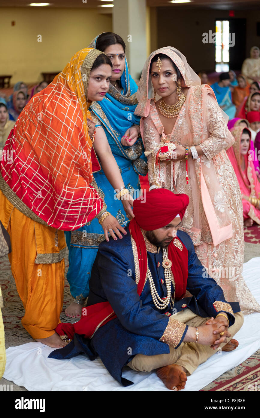 Drei Frauen Attendants & der Bräutigam an seiner Hochzeit Zeremonie im Tempel in der Sikh Gesellschaft in Richmond Hill, Queens, New York City. Stockfoto