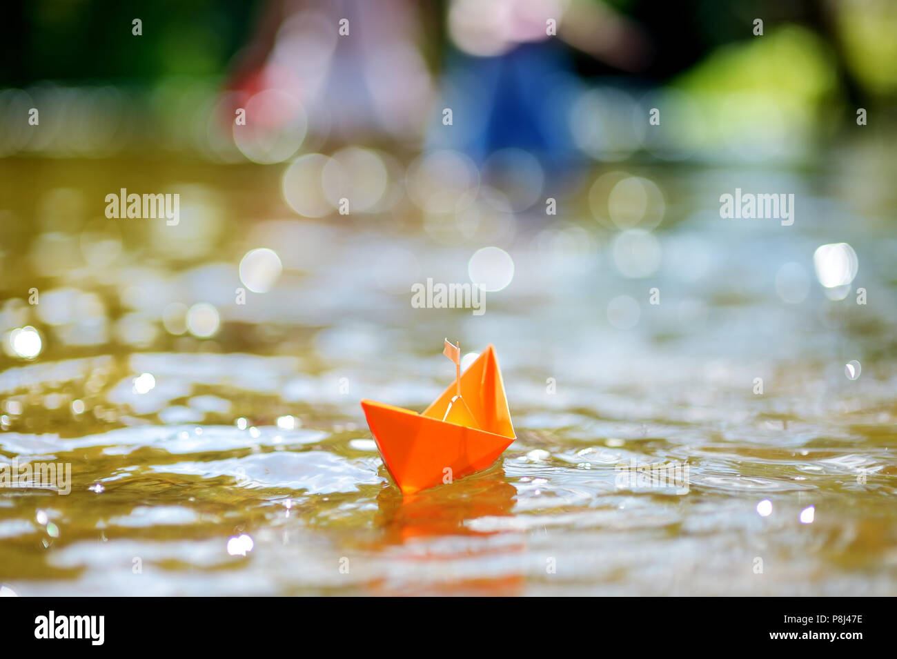 Orange Papier Boot mit einer weißen Fahne schwebend an einem Fluss Stockfoto