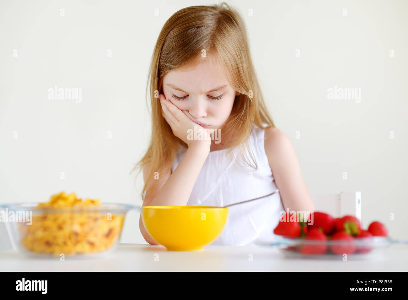 Adorable kleine Mädchen mit Müsli mit Erdbeeren in weißer Küche Stockfoto