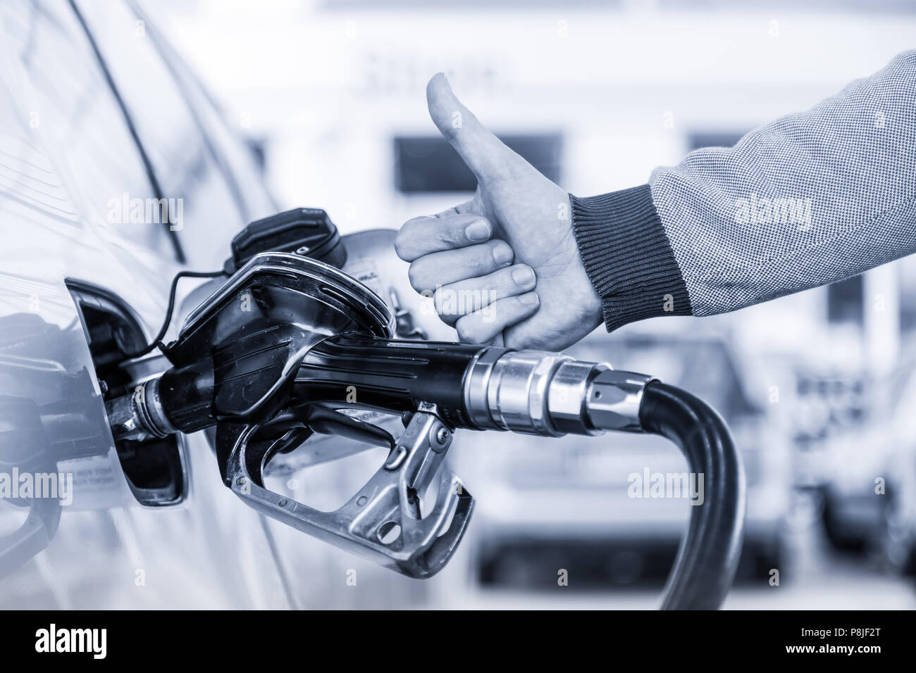 Benzin oder Benzin in ein Kraftfahrzeug Auto gepumpt. Nahaufnahme des Menschen, zeigt Daumen oben Geste, Pumpen Benzin Kraftstoff im Auto an Tankstelle. Stockfoto