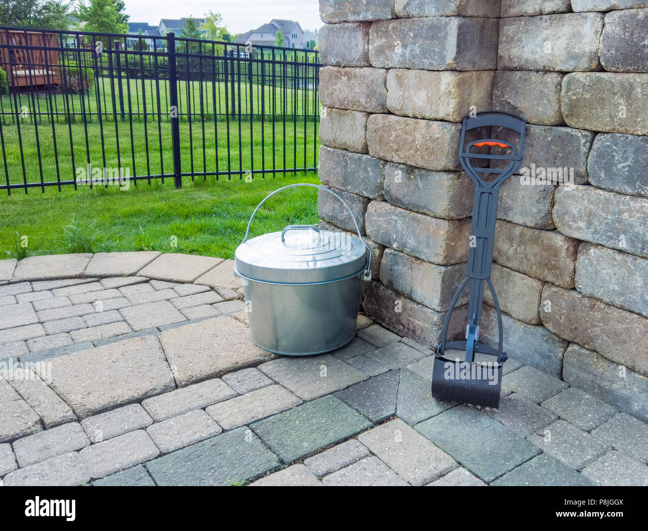 Pooper scooper und Metall Eimer in einen Garten ordentlich gespeichert auf äußere Terrasse bereit für das Sammeln von Hund Kot aus der Familie Haustier Stockfoto
