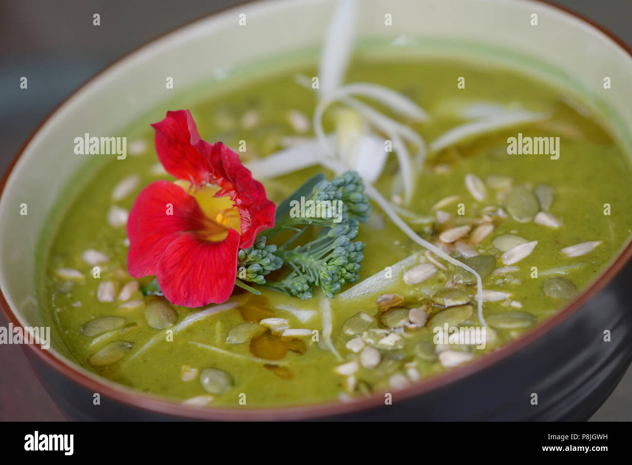 Eine Schüssel mit gesunden grünen Göttin hausgemachte Suppe aus frisch pürierte organische Grüns und Gemüse mit Kapuzinerkresse und kürbiskerne eingerichtet Stockfoto