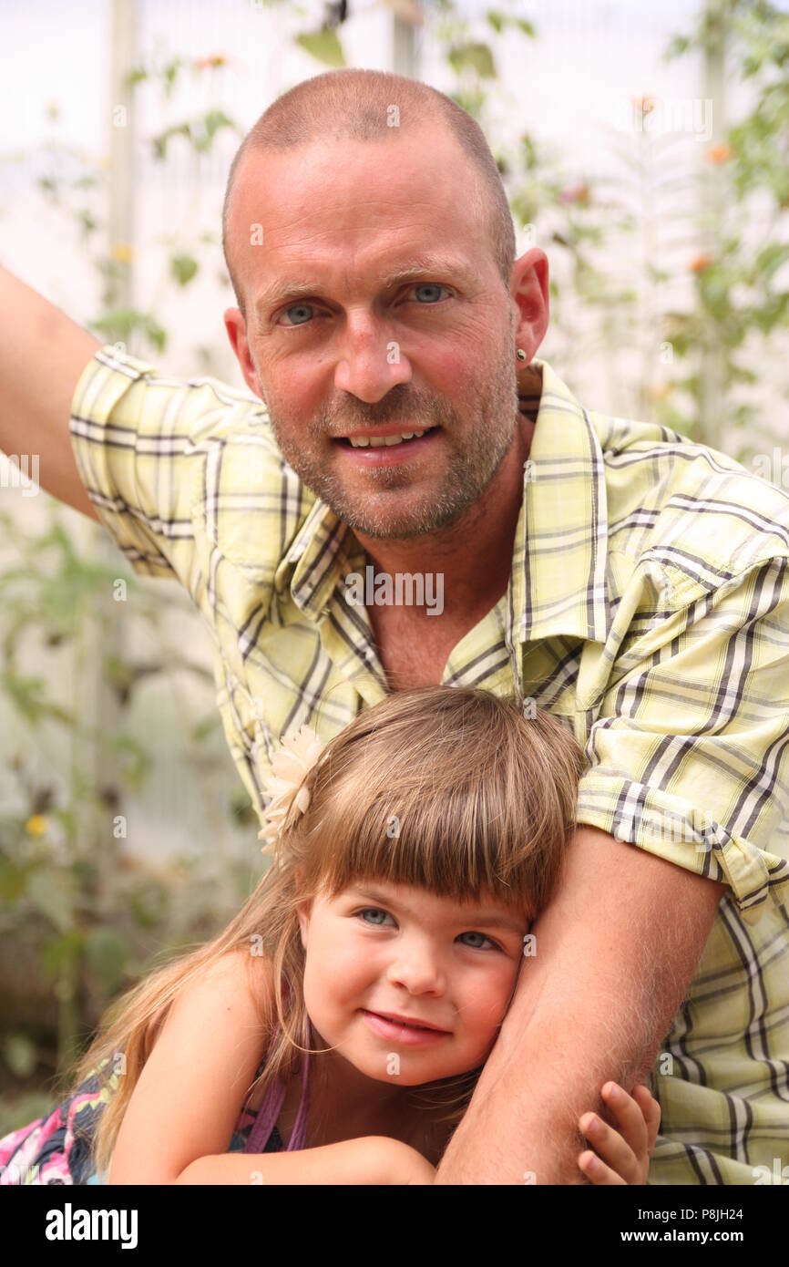 Vater im gelben Hemd kuscheln toddler Tochter im lila Kleid Stockfoto