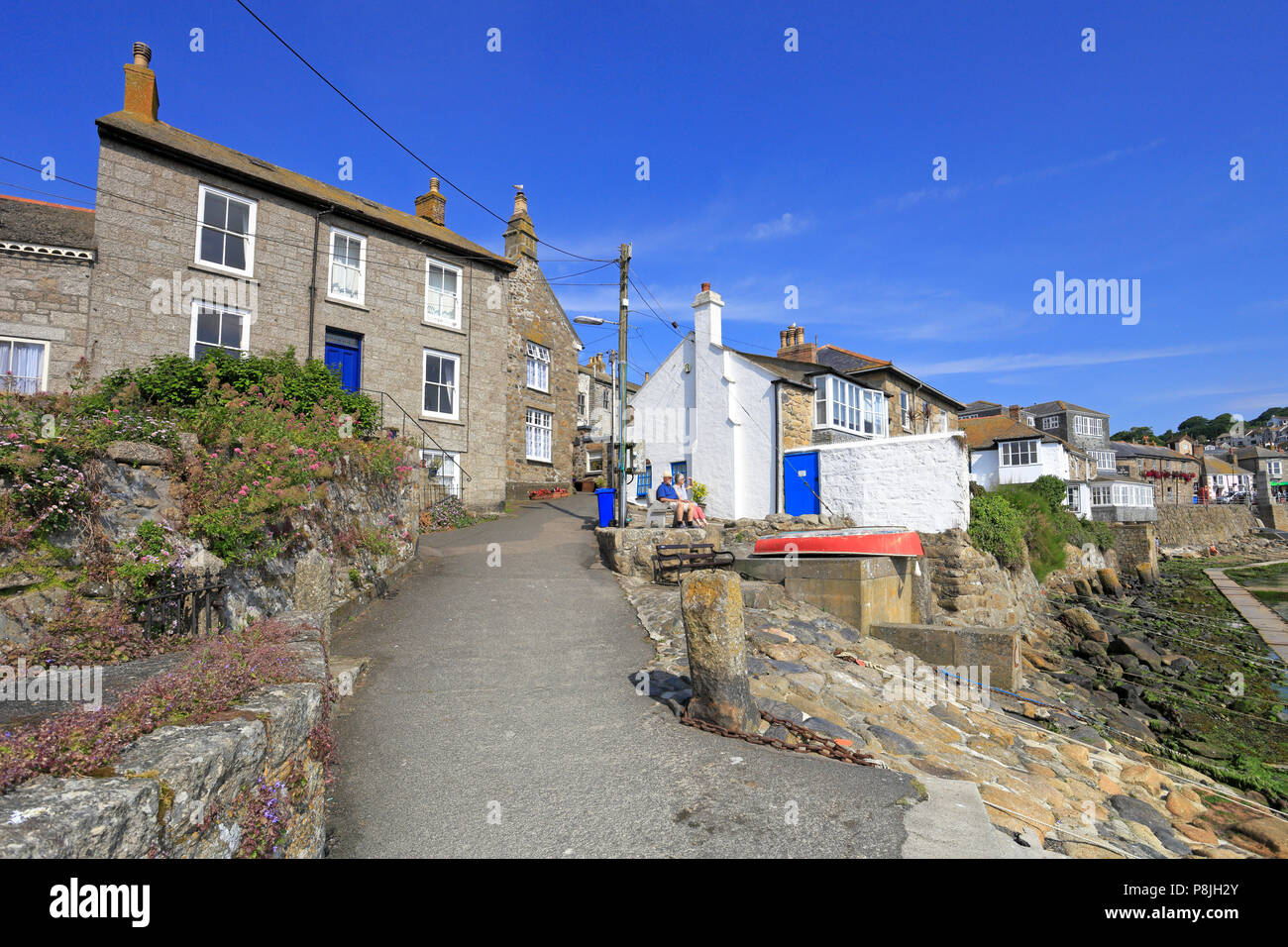 Ein älteres Paar saß auf einer Bank durch eine schmale Straße mit Blick auf den Hafen in Fowey, Cornwall, England, Großbritannien. Stockfoto