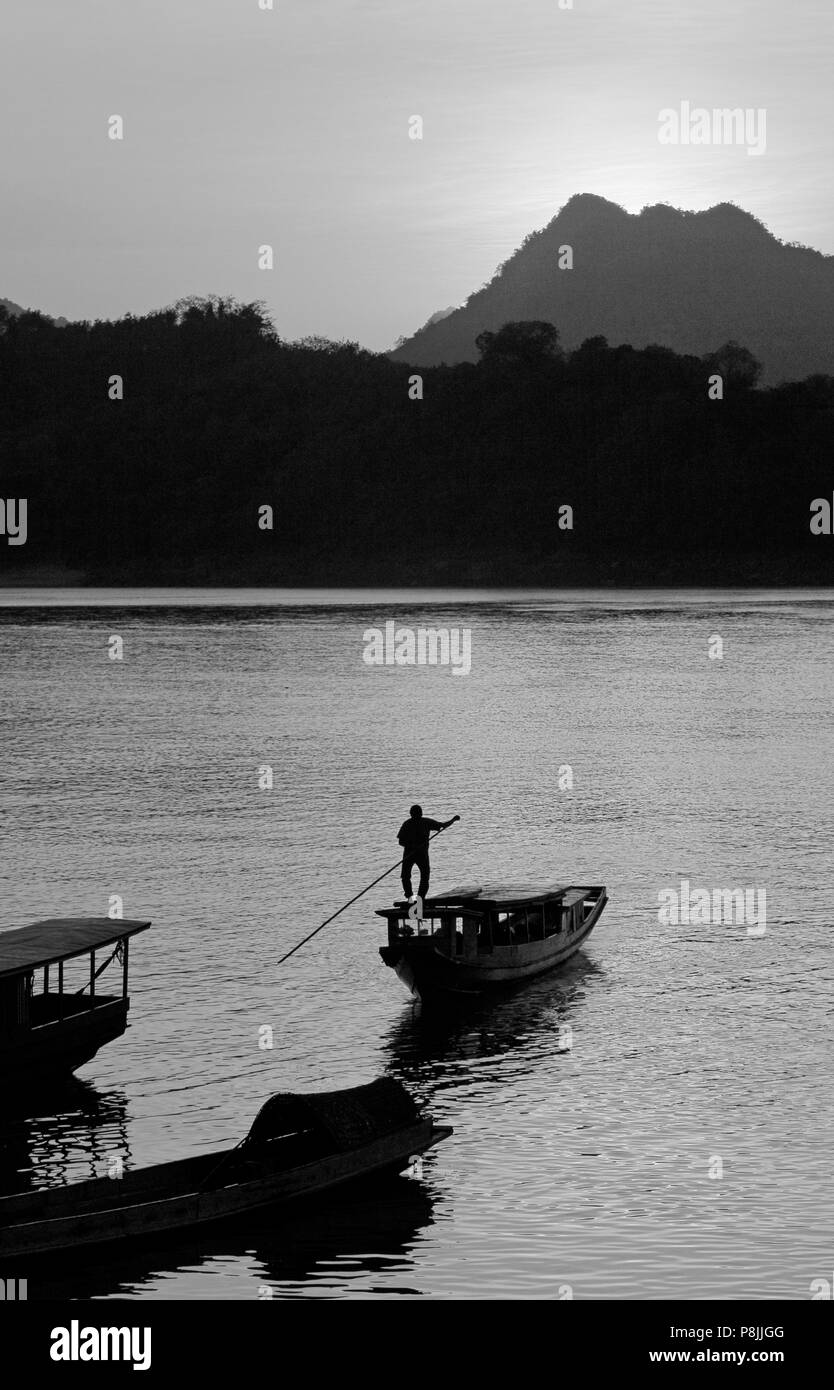 Die Sonnenuntergänge auf dem Mekong Fluss silhouetting ein langsames Schiff, für Transport - LUANG PROBANG, Laos verwendet wird Stockfoto