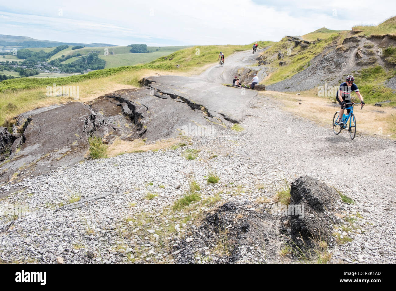 Erdrutsch Straße beschädigt werden. Radfahrer Radfahren auf den beschädigten Road (A625) unter Mam Tor, Derbyshire, England, Großbritannien Stockfoto