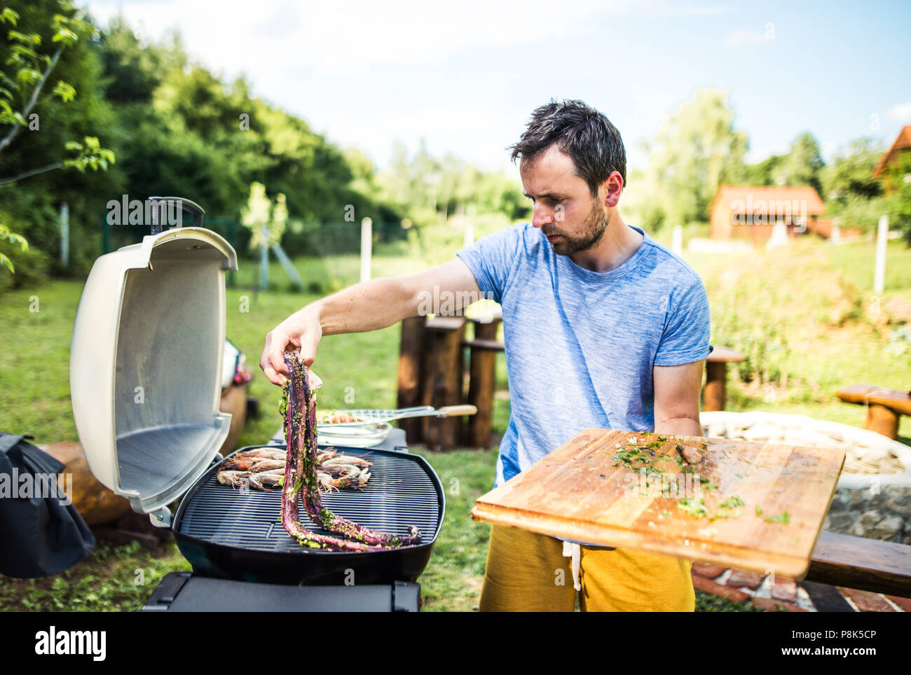 Reifer mann Kochen Fisch auf dem Grill im Hof. Stockfoto