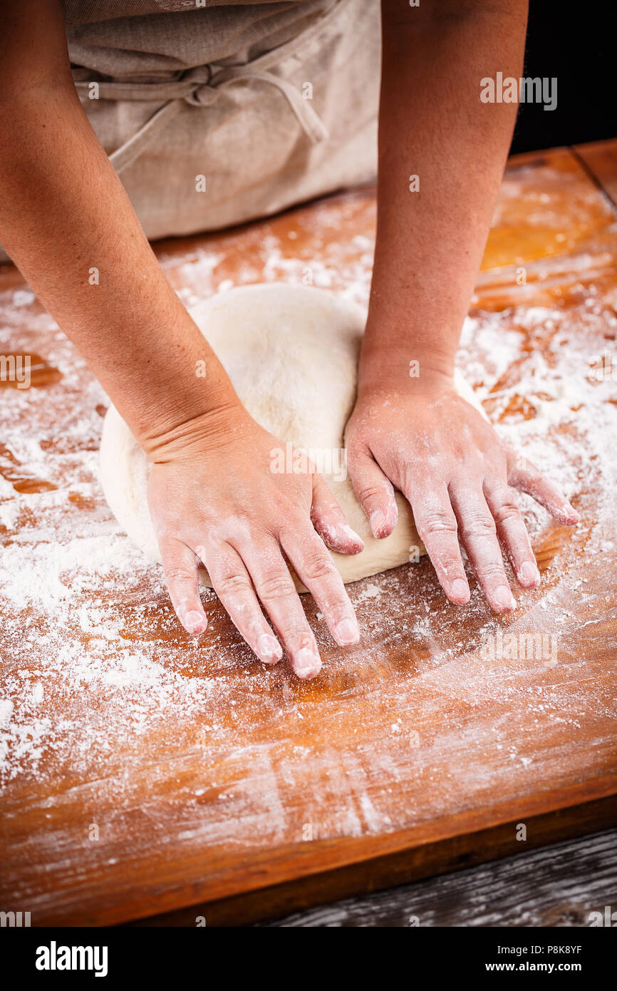 Frauenhand Knetteig auf einem Tisch Stockfoto