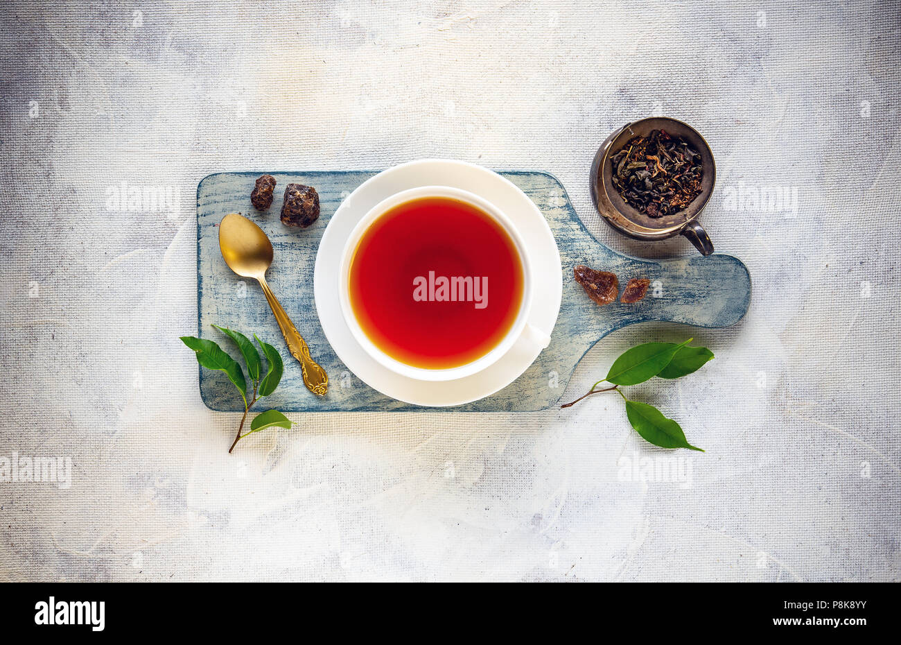 Tee Zusammensetzung mit Tasse Tee, getrocknete und frische Teeblätter und Rock von Zucker Stockfoto