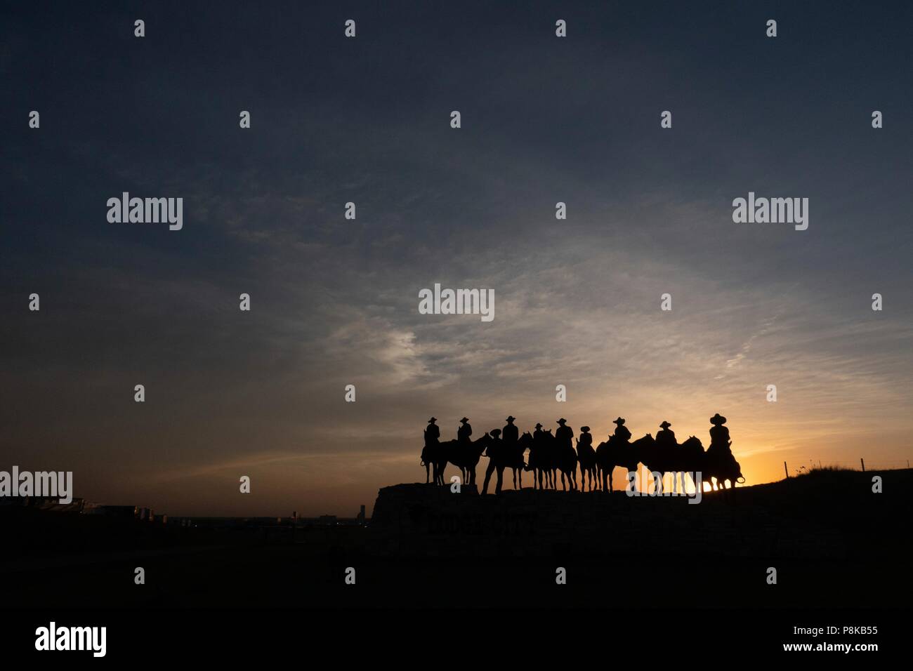 Silhouette Skulptur von Cowboys auf dem Pferd bei Sonnenuntergang in Dodge City, Kansas Stockfoto