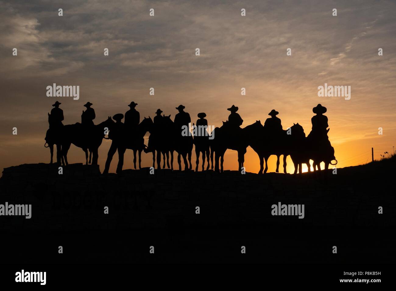 Silhouette Skulptur von Cowboys auf dem Pferd bei Sonnenuntergang in Dodge City, Kansas Stockfoto