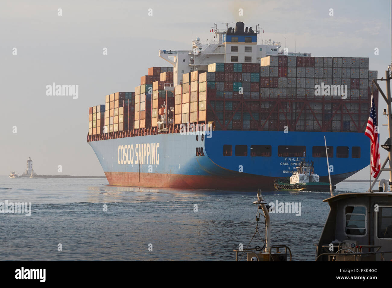 Stern angesichts der riesigen COSCO Container schiff, CSCL HERBST Auslaufen aus dem Hafen von Los Angeles, die Engel Tor Leuchtturm auf der linken Seite. Stockfoto