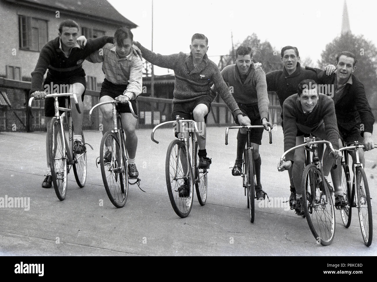 1950er Jahre, Gruppe männlicher Bahnradfahrer Line-up zusammen auf ihre Fahrräder auf dem Bankkonto Anschluss außerhalb, England, UK. In der Sport der Schiene Radfahren, die an speziell dafür gebauten banked Titel oder velodromes, die Räder haben keine Bremsen oder Getriebe oder so ist es eine der reinsten Formen der Bike Racing. Club Track Radfahren war eine beliebte Freizeitbeschäftigung in Großbritannien in den 40er und 50er Jahren. Stockfoto