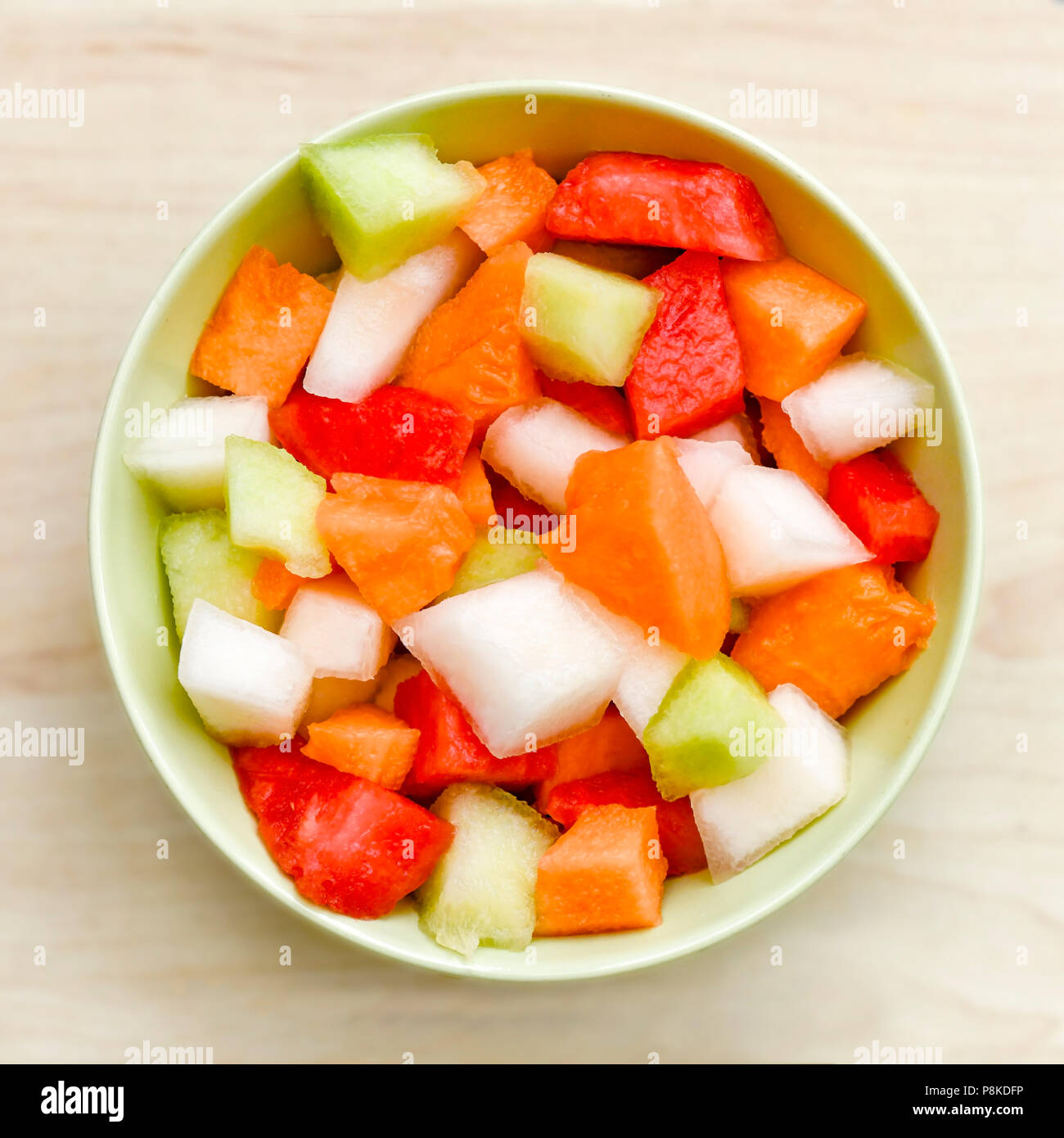 Über quadratischen Kopf Bild des geschnittenen Melone Stücke in Rot, Grün, Gelb und Orange in einer runden Schüssel, Hintergrund verschwommen zu Anzeige Kopie Raum Stockfoto