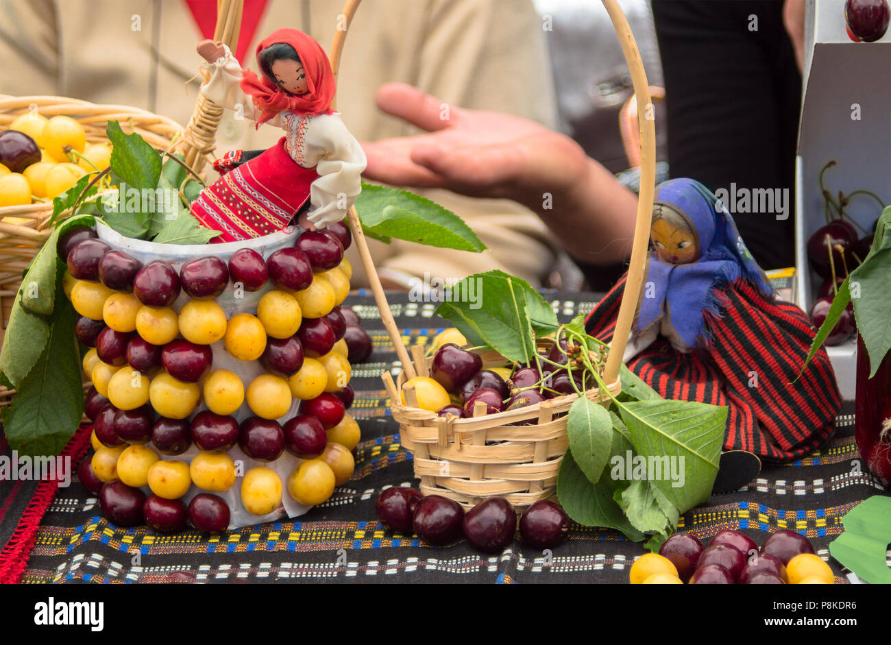 Gelb in roten Kirschen. Mit Puppen in der bulgarischen nationalen Kostüme und Stoffen mit Bulgarian Folk Elementen dekoriert. Stockfoto
