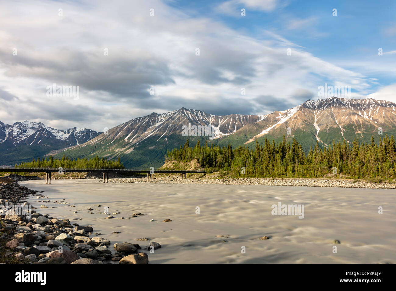 Abendsonne auf der Sommersonnenwende beleuchtet die Kennicott River, Wrangell Bergen und der Fußgängerbrücke zur McCarthy in Alaska. Stockfoto