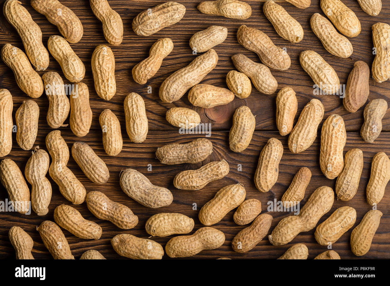 Hintergrund spiralförmige Muster von Kreisen ganz natürliche Erdnüsse in der Schale oder Pods auf einem hölzernen Tisch von oben gesehen Stockfoto