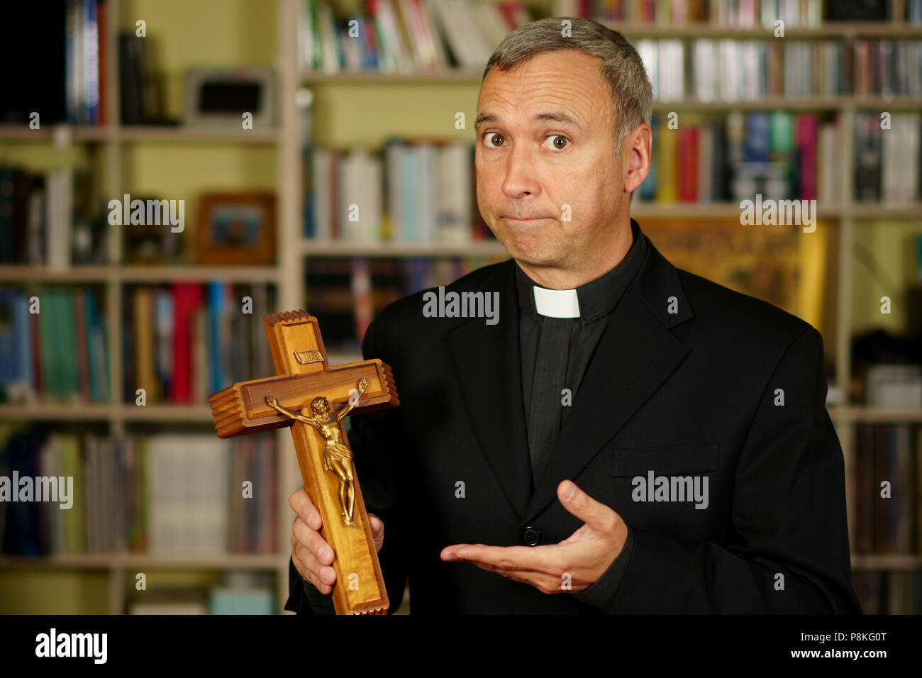 Ein katholischer Priester, ein Kruzifix. Er schaut ernst zu nehmen, uns mit Interesse, Nachdenklichkeit und Missionierung. Stockfoto