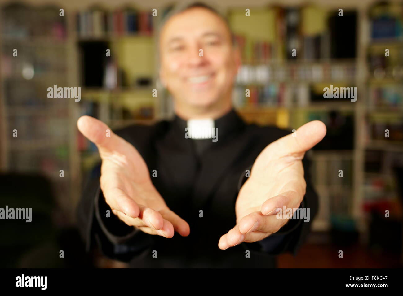 Ein katholischer Priester ist seine Hände öffnen die Freude Christi zu bieten. Er schaut uns mit Freude, Frieden und Optimismus. Konzentrieren Sie sich auf die Hände. Stockfoto