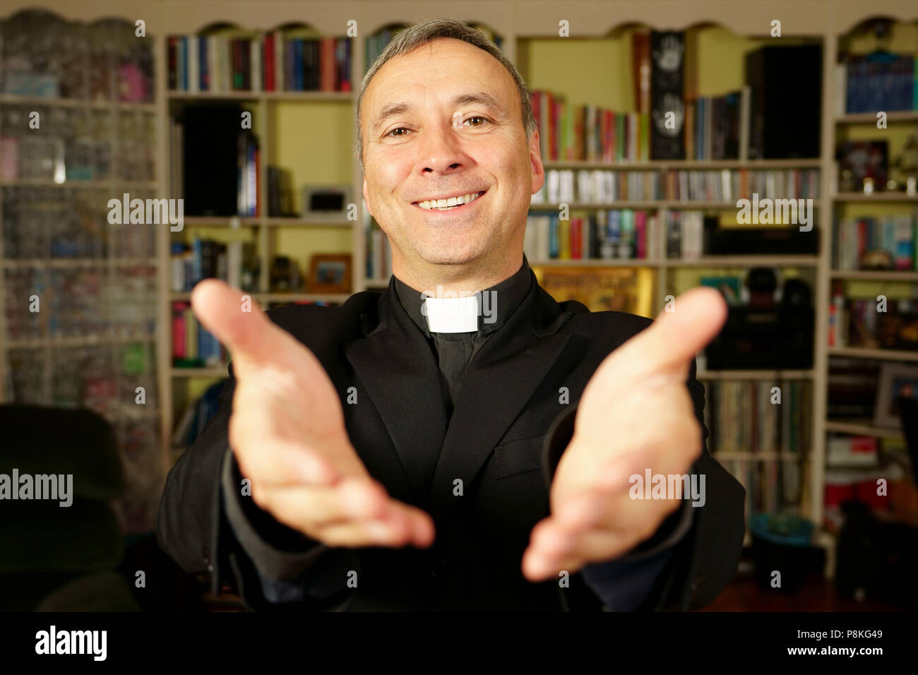 Ein katholischer Priester ist seine Hände öffnen die Freude Christi zu bieten. Er schaut uns mit Freude, Frieden und Optimismus. Fokus auf das Gesicht. Stockfoto