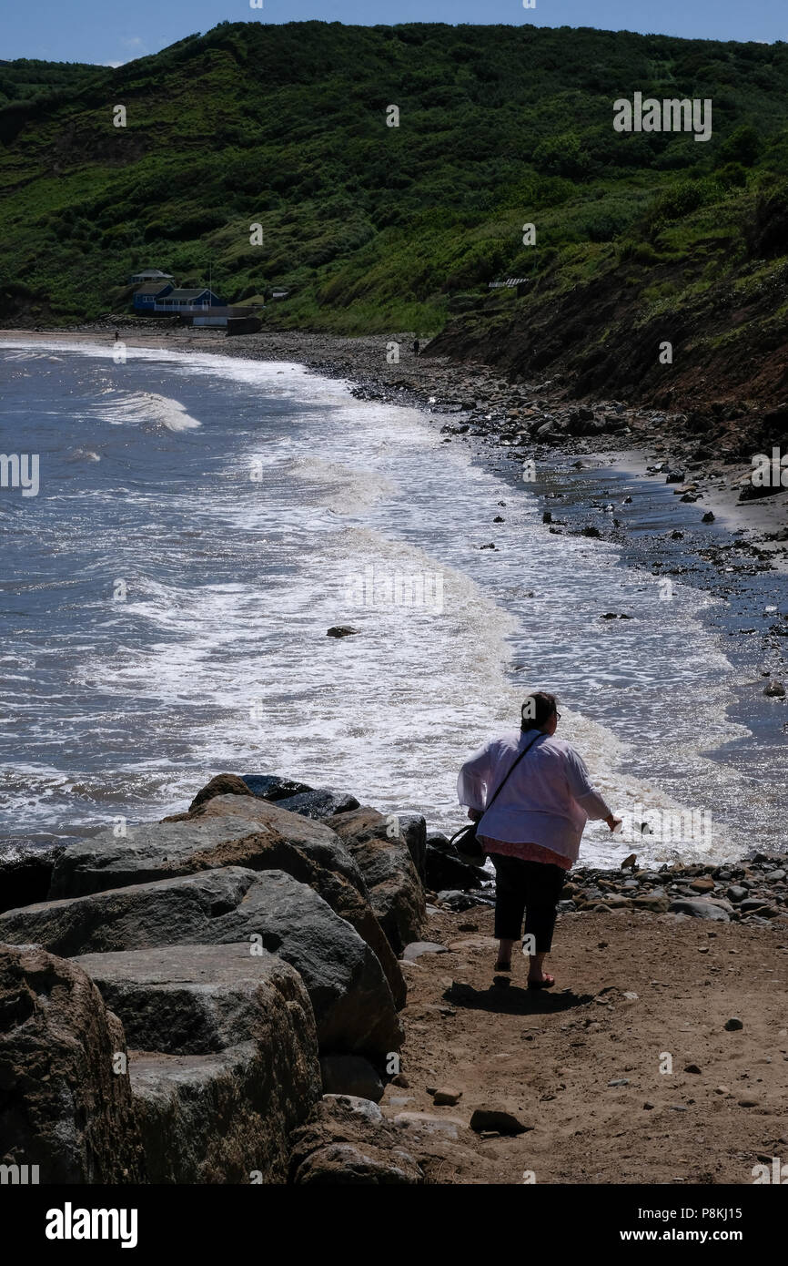 Urlauber und Menschen zu Fuß die Felsen am Strand mit Hund am Meer auf [Songbook] Bay, North Yorkshire Heritage Coast. Stockfoto
