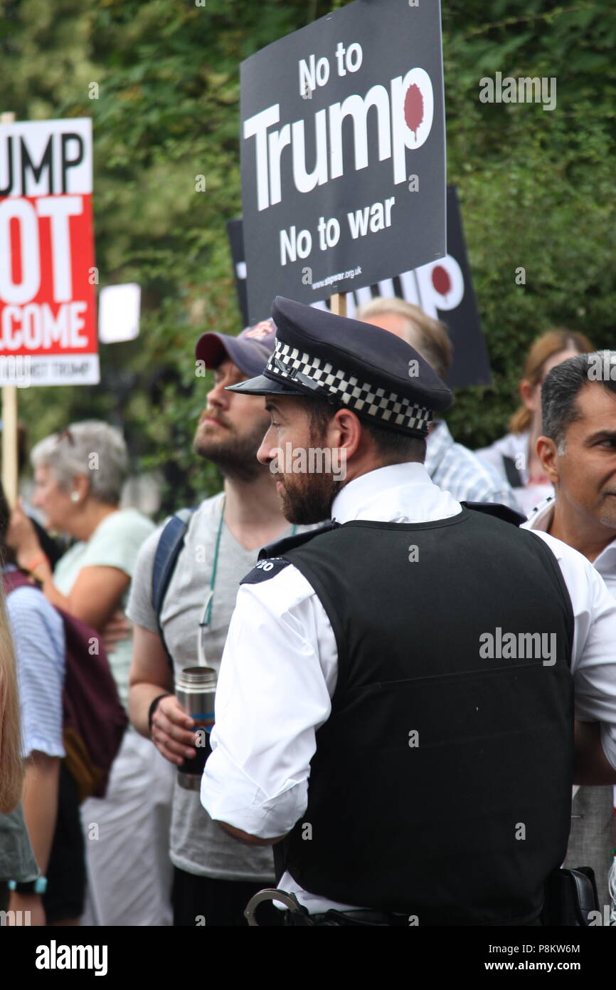London, UK, 12. Juli 2018. Ein Polizist Kontrollen anti-Trump Demonstranten vor der Residenz des Botschafters, wie der US-Präsident besucht Großbritannien. Roland Ravenhill/Alamy leben Nachrichten Stockfoto