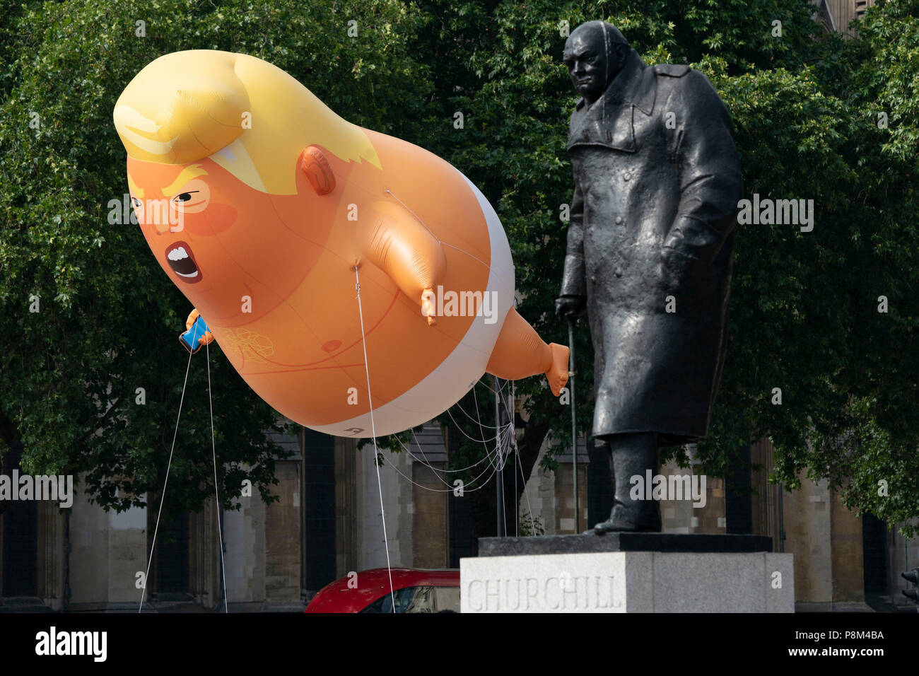 LONDON - Juli 13: Ein Donald Trump baby Ballon fliegt neben der Statue von Winston Churchill in Parliament Square in London am 13. Juli 2018, während des Besuchs in Großbritannien durch US-Präsident, Donald Trump. Foto von David Levenson Credit: David Levenson/Alamy leben Nachrichten Stockfoto