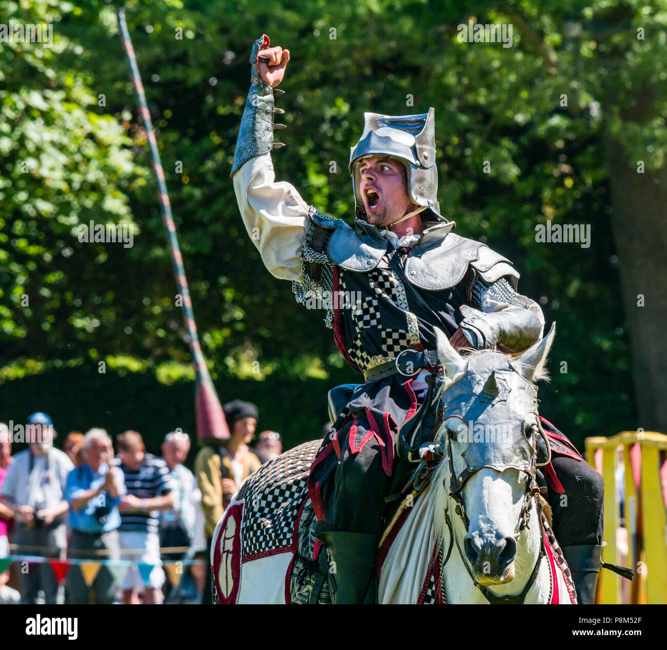 Medieval Jousting, Linlithgow Palace, Schottland, Großbritannien. HES Sommer Unterhaltung von Les Amis D'Onno equine stunt Team. Ein Ritter zu Pferd Cheers Stockfoto