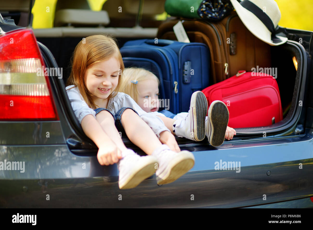 Zwei entzückenden kleinen Schwestern in einem Auto sitzen nur vor dem Verlassen für ein Auto Urlaub mit ihren Eltern Stockfoto